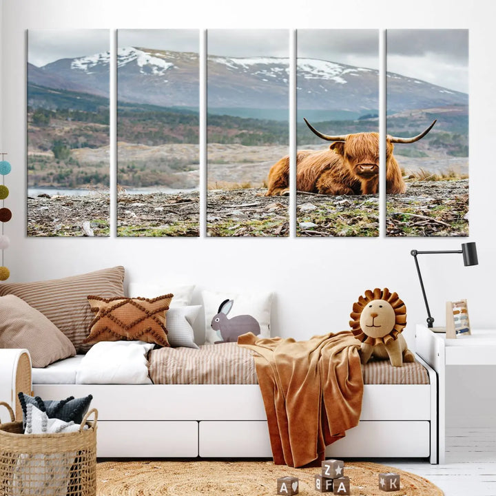 The Highland Cow Horn Farm Wall Art Canvas Print showcases a serene scene of a highland cow resting with snow-capped mountains in the background. This three-panel, museum-quality canvas features a UV-protective coating and is ready to hang.