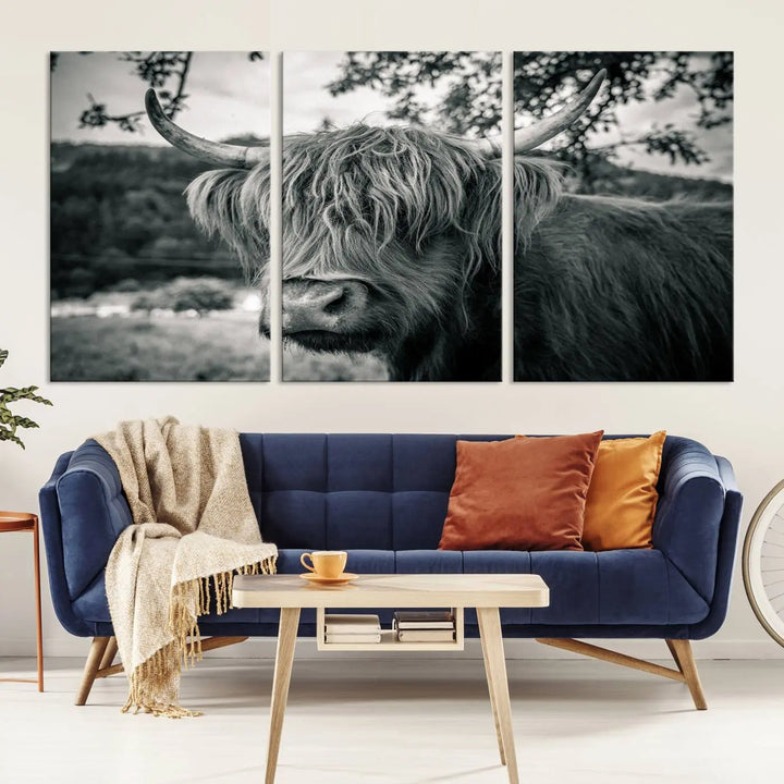 The stylish living room showcases the "Highland Cow Wall Art Canvas Print Scottish Cattle Canvas Art" displayed as a triptych on the wall. This artwork is gallery wrapped on museum-quality canvas with a UV-protective coating for lasting elegance.