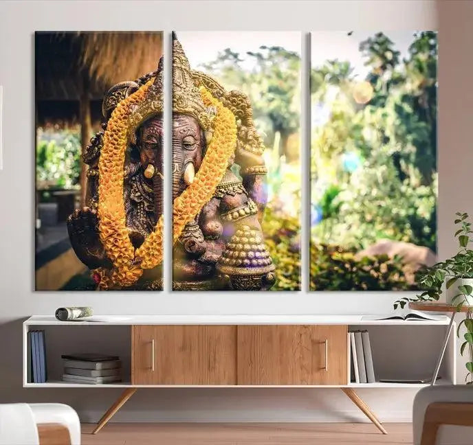 A set of three panels depicting the Hindu deity Lord Ganesha, embellished with a yellow garland, gracefully decorates a wall. This gallery-wrapped artwork, known as the Hinduism Statue Wall Art Canvas Print, is meticulously crafted on museum-quality canvas for an exquisite finish.