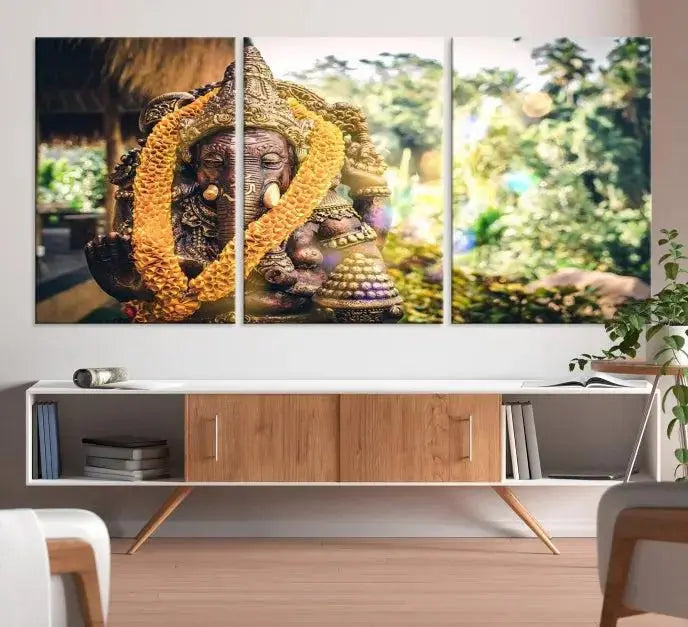 A set of three panels depicting the Hindu deity Lord Ganesha, embellished with a yellow garland, gracefully decorates a wall. This gallery-wrapped artwork, known as the Hinduism Statue Wall Art Canvas Print, is meticulously crafted on museum-quality canvas for an exquisite finish.