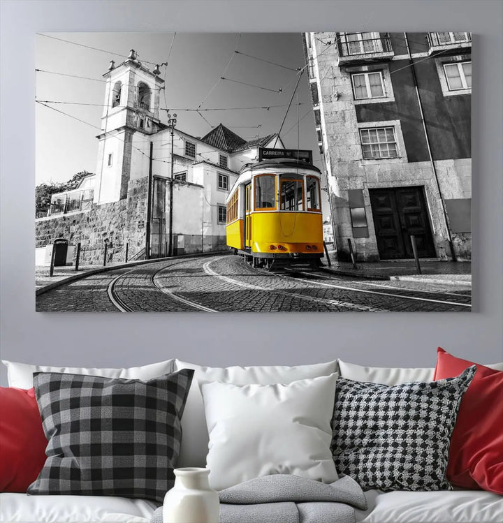 The Iconic Yellow Lisbon Tram Canvas Wall Art Print showcases a yellow tram navigating through a monochrome street scene, with a historic building in the background, exquisitely captured on museum-quality canvas.