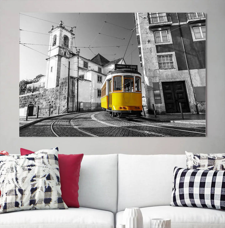 The Iconic Yellow Lisbon Tram Canvas Wall Art Print showcases a yellow tram navigating through a monochrome street scene, with a historic building in the background, exquisitely captured on museum-quality canvas.