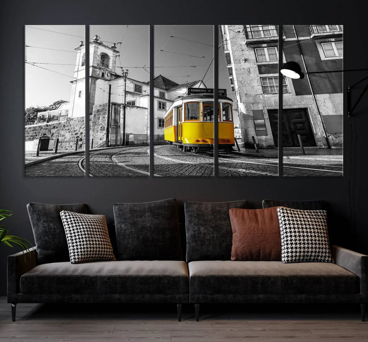 The Iconic Yellow Lisbon Tram Canvas Wall Art Print showcases a yellow tram navigating through a monochrome street scene, with a historic building in the background, exquisitely captured on museum-quality canvas.