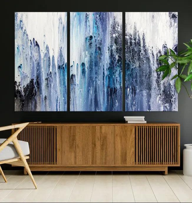 The minimalist room is adorned with the Ink Abstract Wall Art Canvas Print, featuring a museum-quality triptych in blue and white elegantly displayed. Rendered on UV-protective canvas for lasting vibrancy.