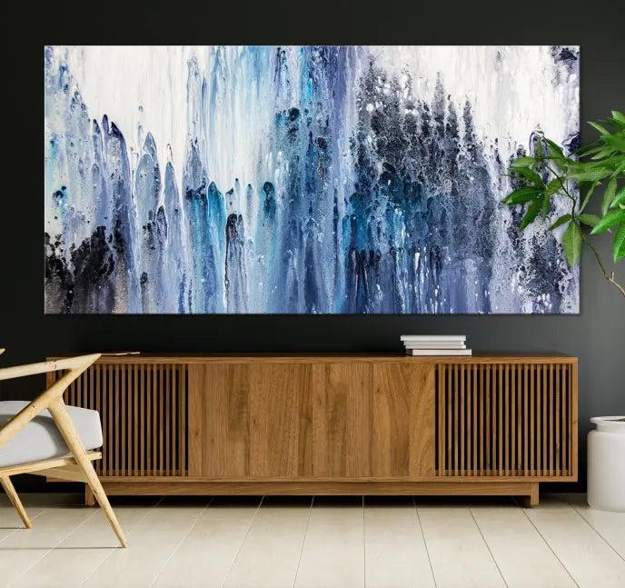 The minimalist room is adorned with the Ink Abstract Wall Art Canvas Print, featuring a museum-quality triptych in blue and white elegantly displayed. Rendered on UV-protective canvas for lasting vibrancy.