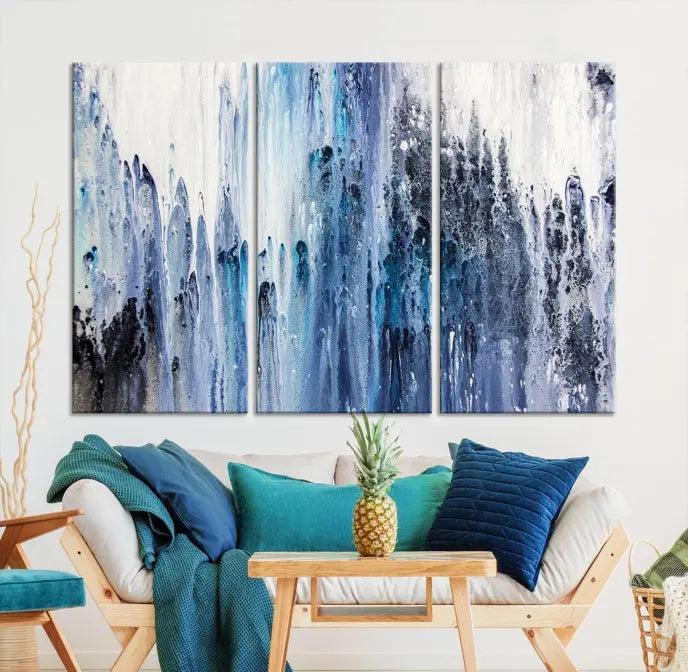 The minimalist room is adorned with the Ink Abstract Wall Art Canvas Print, featuring a museum-quality triptych in blue and white elegantly displayed. Rendered on UV-protective canvas for lasting vibrancy.