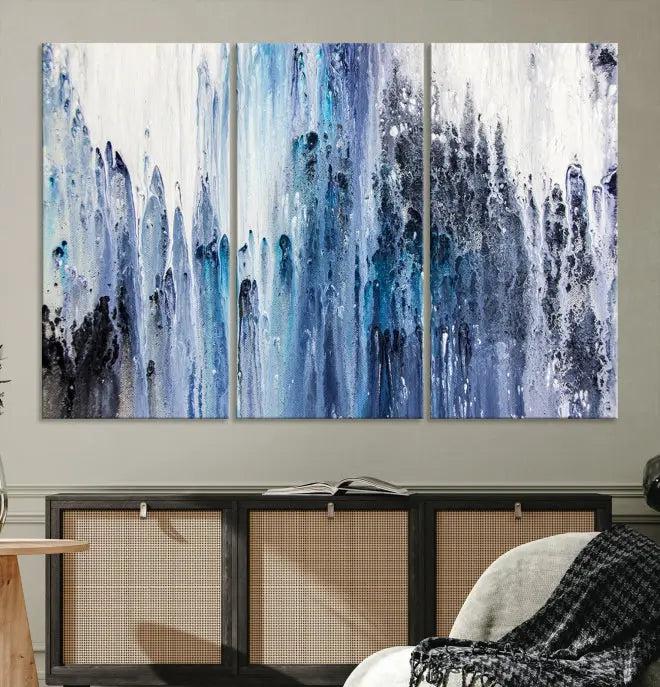 The minimalist room is adorned with the Ink Abstract Wall Art Canvas Print, featuring a museum-quality triptych in blue and white elegantly displayed. Rendered on UV-protective canvas for lasting vibrancy.