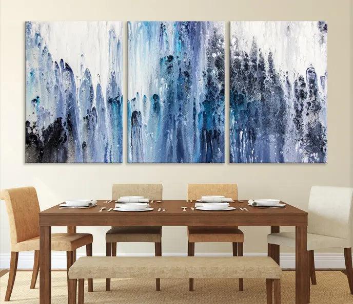 The minimalist room is adorned with the Ink Abstract Wall Art Canvas Print, featuring a museum-quality triptych in blue and white elegantly displayed. Rendered on UV-protective canvas for lasting vibrancy.