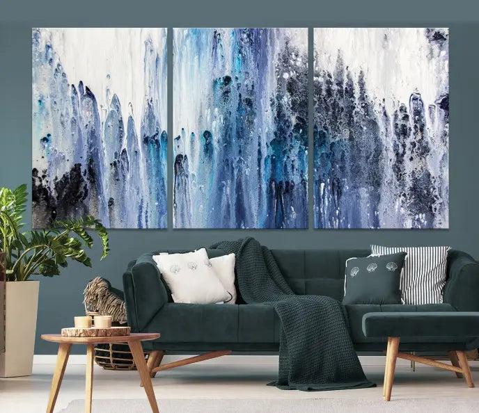 The minimalist room is adorned with the Ink Abstract Wall Art Canvas Print, featuring a museum-quality triptych in blue and white elegantly displayed. Rendered on UV-protective canvas for lasting vibrancy.