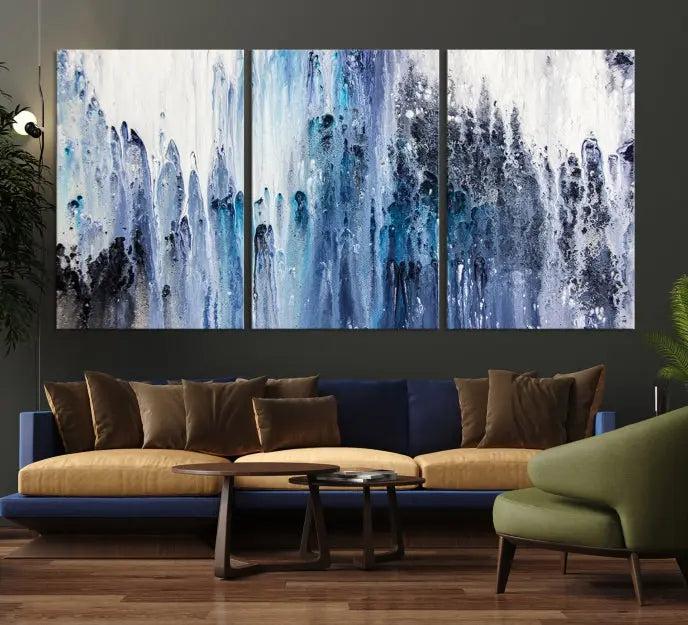 The minimalist room is adorned with the Ink Abstract Wall Art Canvas Print, featuring a museum-quality triptych in blue and white elegantly displayed. Rendered on UV-protective canvas for lasting vibrancy.