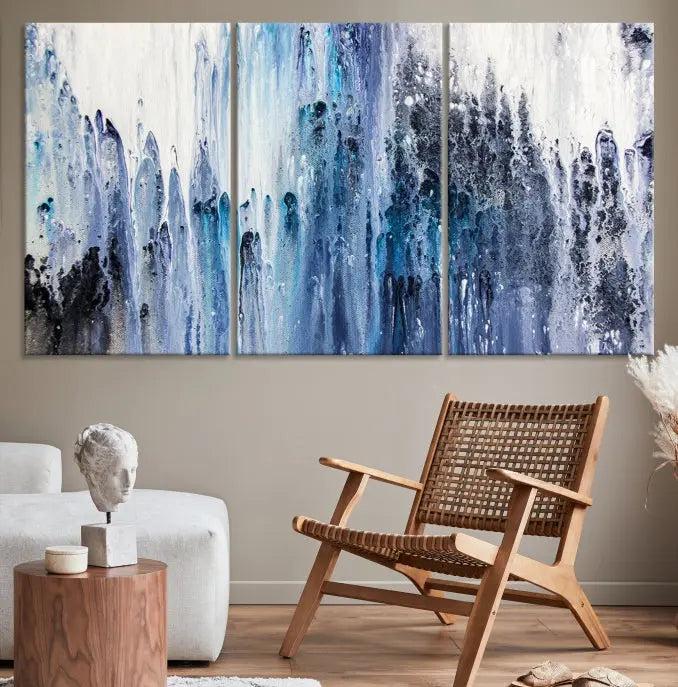 The minimalist room is adorned with the Ink Abstract Wall Art Canvas Print, featuring a museum-quality triptych in blue and white elegantly displayed. Rendered on UV-protective canvas for lasting vibrancy.