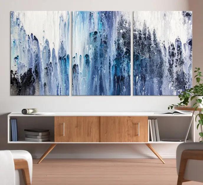 The minimalist room is adorned with the Ink Abstract Wall Art Canvas Print, featuring a museum-quality triptych in blue and white elegantly displayed. Rendered on UV-protective canvas for lasting vibrancy.