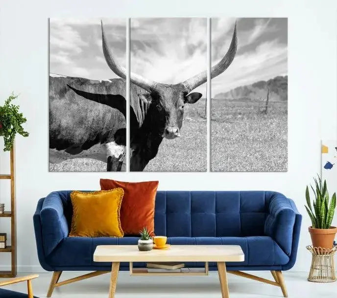 The Longhorn Wall Art Canvas Print, a black and white triptych of a longhorn cow in a grassy field, is elegantly displayed on museum-quality canvases.