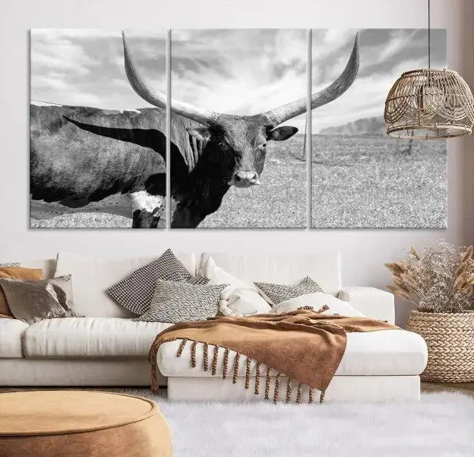 The Longhorn Wall Art Canvas Print, a black and white triptych of a longhorn cow in a grassy field, is elegantly displayed on museum-quality canvases.