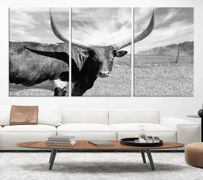 The Longhorn Wall Art Canvas Print, a black and white triptych of a longhorn cow in a grassy field, is elegantly displayed on museum-quality canvases.