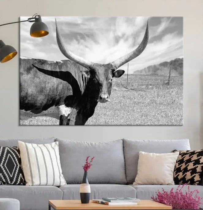 The Longhorn Wall Art Canvas Print, a black and white triptych of a longhorn cow in a grassy field, is elegantly displayed on museum-quality canvases.