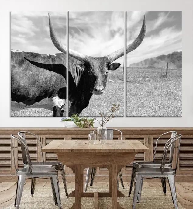 The Longhorn Wall Art Canvas Print, a black and white triptych of a longhorn cow in a grassy field, is elegantly displayed on museum-quality canvases.