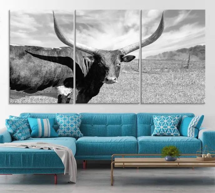 The Longhorn Wall Art Canvas Print, a black and white triptych of a longhorn cow in a grassy field, is elegantly displayed on museum-quality canvases.