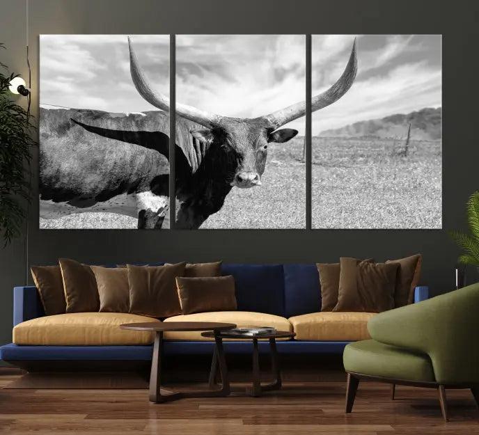 The Longhorn Wall Art Canvas Print, a black and white triptych of a longhorn cow in a grassy field, is elegantly displayed on museum-quality canvases.