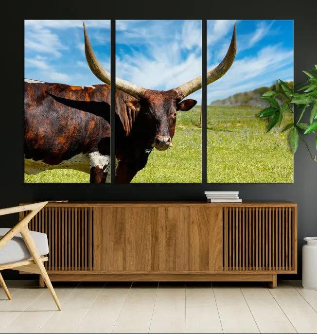 The Longhorn and Cow Wall Art Canvas Print features a triptych of a longhorn cow in a grassy field on a sunny day. These gallery-wrapped, museum-quality canvases are crafted by professional craftsmen to perfectly accentuate the scene, adding an exquisite touch to any living space.