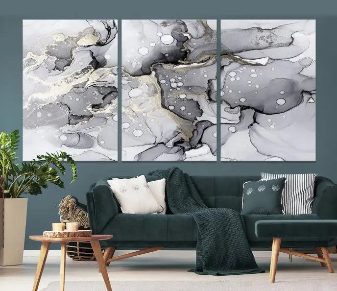 The "Marble Fluid Effect Wall Art Abstract Canvas Wall Art Print" forms a stunning abstract triptych with black, gray, and gold patterns in a modern living room. These museum-quality pieces include a UV-protective coating to ensure lasting beauty.