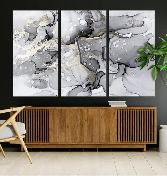 The "Marble Fluid Effect Wall Art Abstract Canvas Wall Art Print" forms a stunning abstract triptych with black, gray, and gold patterns in a modern living room. These museum-quality pieces include a UV-protective coating to ensure lasting beauty.