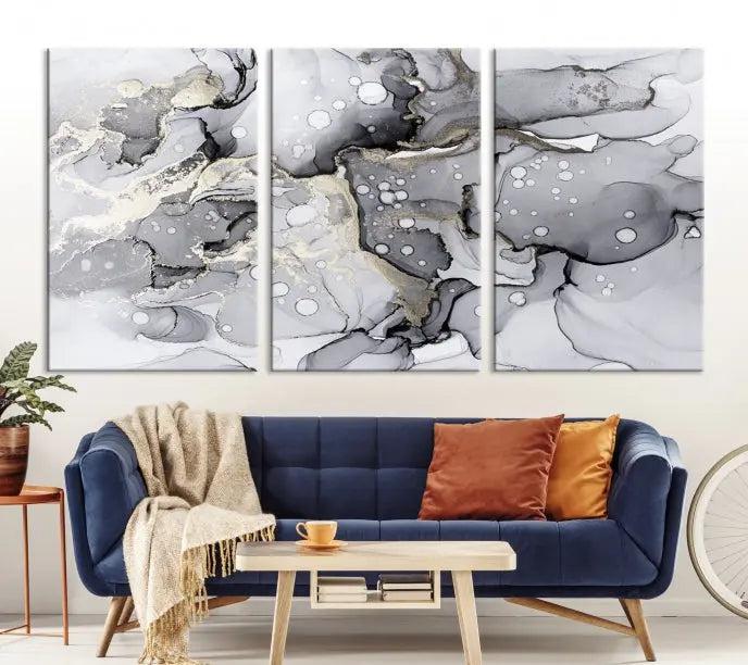 The "Marble Fluid Effect Wall Art Abstract Canvas Wall Art Print" forms a stunning abstract triptych with black, gray, and gold patterns in a modern living room. These museum-quality pieces include a UV-protective coating to ensure lasting beauty.