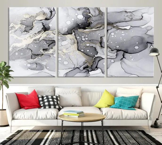 The "Marble Fluid Effect Wall Art Abstract Canvas Wall Art Print" forms a stunning abstract triptych with black, gray, and gold patterns in a modern living room. These museum-quality pieces include a UV-protective coating to ensure lasting beauty.