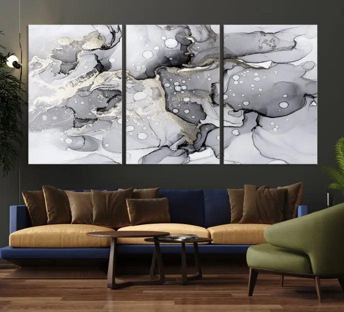 The "Marble Fluid Effect Wall Art Abstract Canvas Wall Art Print" forms a stunning abstract triptych with black, gray, and gold patterns in a modern living room. These museum-quality pieces include a UV-protective coating to ensure lasting beauty.