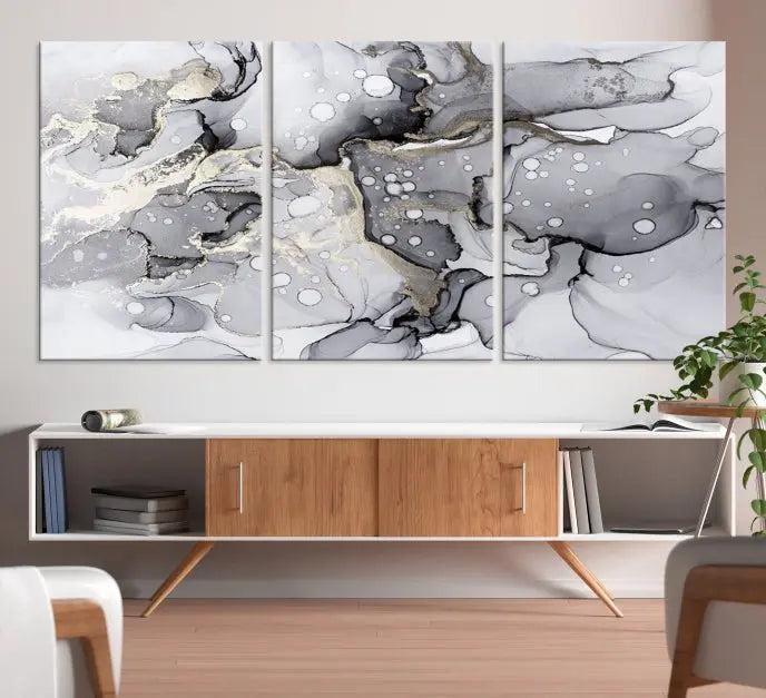 The "Marble Fluid Effect Wall Art Abstract Canvas Wall Art Print" forms a stunning abstract triptych with black, gray, and gold patterns in a modern living room. These museum-quality pieces include a UV-protective coating to ensure lasting beauty.