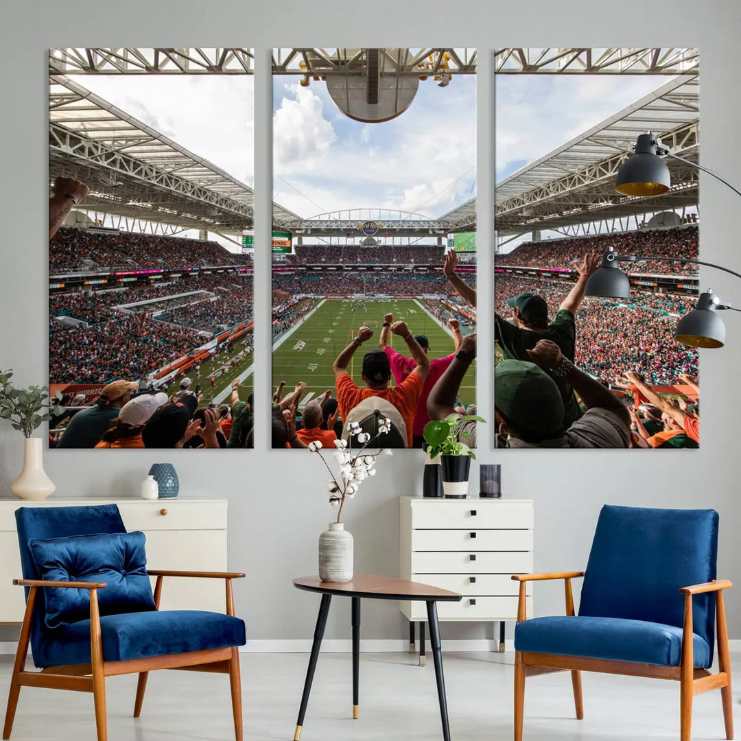 The living room features handmade triptych wall art crafted in the USA, depicting a cheering crowd at a Miami Hurricanes football game. The artwork showcases the Miami Hard Rock Stadium on premium canvas.