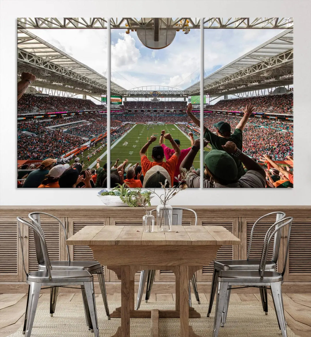 The living room features handmade triptych wall art crafted in the USA, depicting a cheering crowd at a Miami Hurricanes football game. The artwork showcases the Miami Hard Rock Stadium on premium canvas.