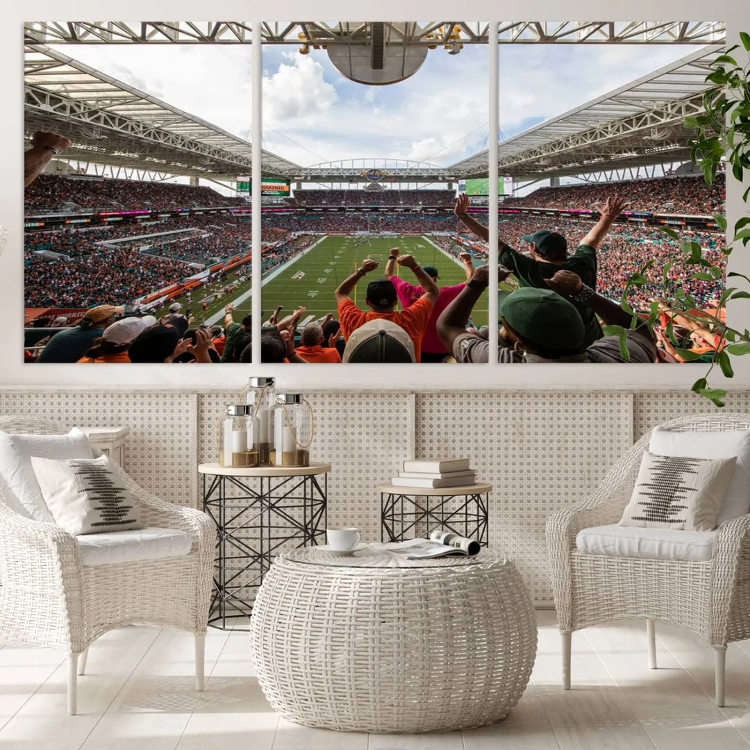 The living room features handmade triptych wall art crafted in the USA, depicting a cheering crowd at a Miami Hurricanes football game. The artwork showcases the Miami Hard Rock Stadium on premium canvas.