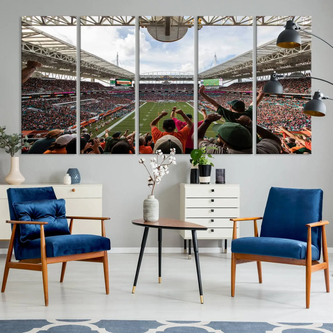 The living room features handmade triptych wall art crafted in the USA, depicting a cheering crowd at a Miami Hurricanes football game. The artwork showcases the Miami Hard Rock Stadium on premium canvas.