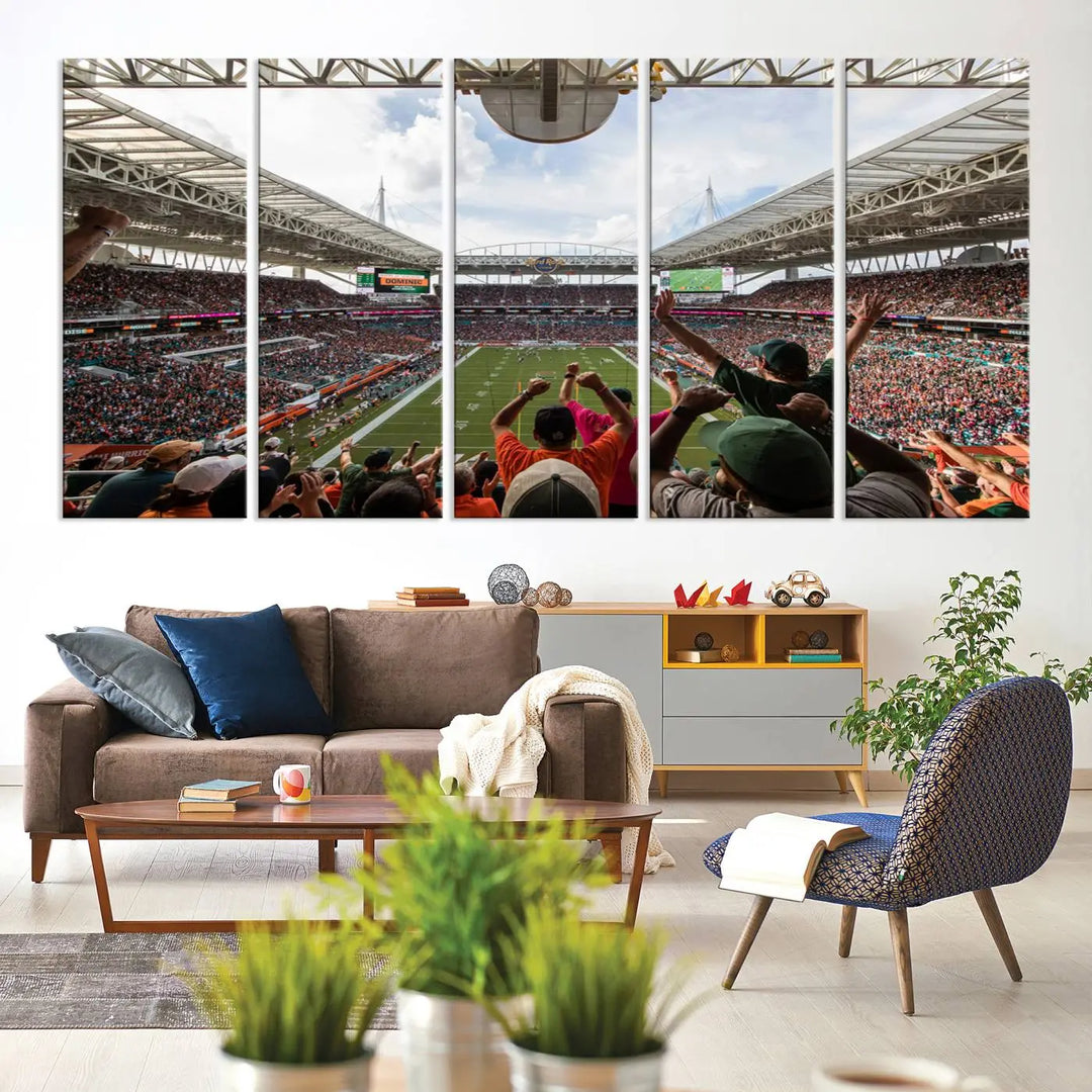 The living room features handmade triptych wall art crafted in the USA, depicting a cheering crowd at a Miami Hurricanes football game. The artwork showcases the Miami Hard Rock Stadium on premium canvas.