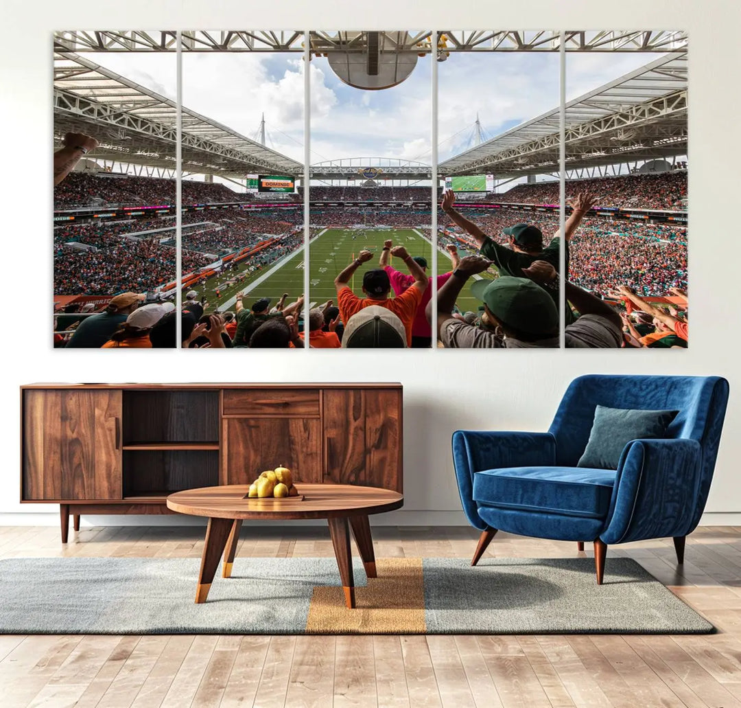 The living room features handmade triptych wall art crafted in the USA, depicting a cheering crowd at a Miami Hurricanes football game. The artwork showcases the Miami Hard Rock Stadium on premium canvas.