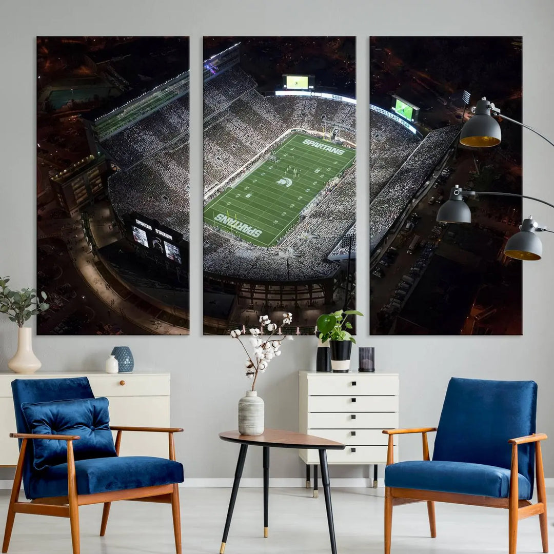 The "Michigan State Spartans Football Team Print - East Lansing Spartan Stadium Wall Art Canvas Print" is elegantly displayed on a wall, showcasing a brightly lit football stadium at night with a gallery-quality finish.