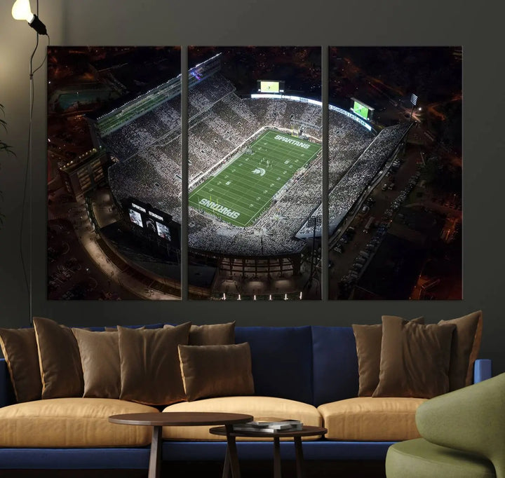 The "Michigan State Spartans Football Team Print - East Lansing Spartan Stadium Wall Art Canvas Print" is elegantly displayed on a wall, showcasing a brightly lit football stadium at night with a gallery-quality finish.