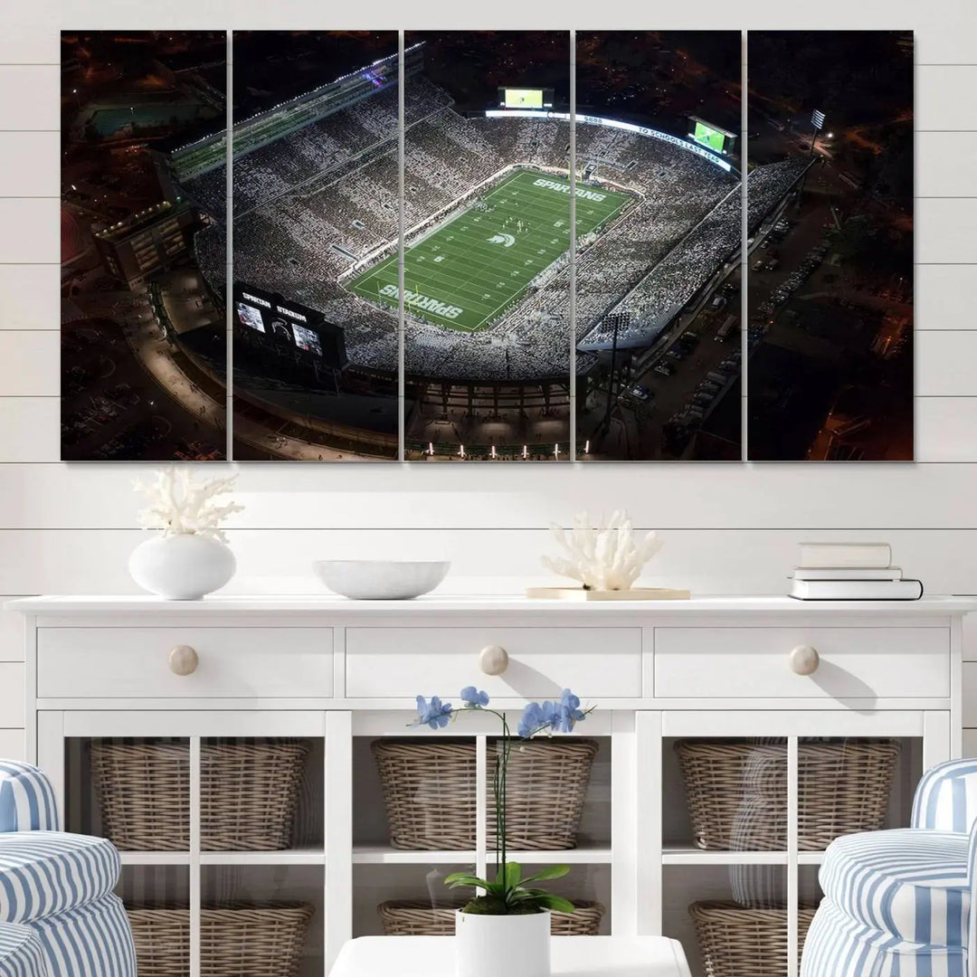 The "Michigan State Spartans Football Team Print - East Lansing Spartan Stadium Wall Art Canvas Print" is elegantly displayed on a wall, showcasing a brightly lit football stadium at night with a gallery-quality finish.