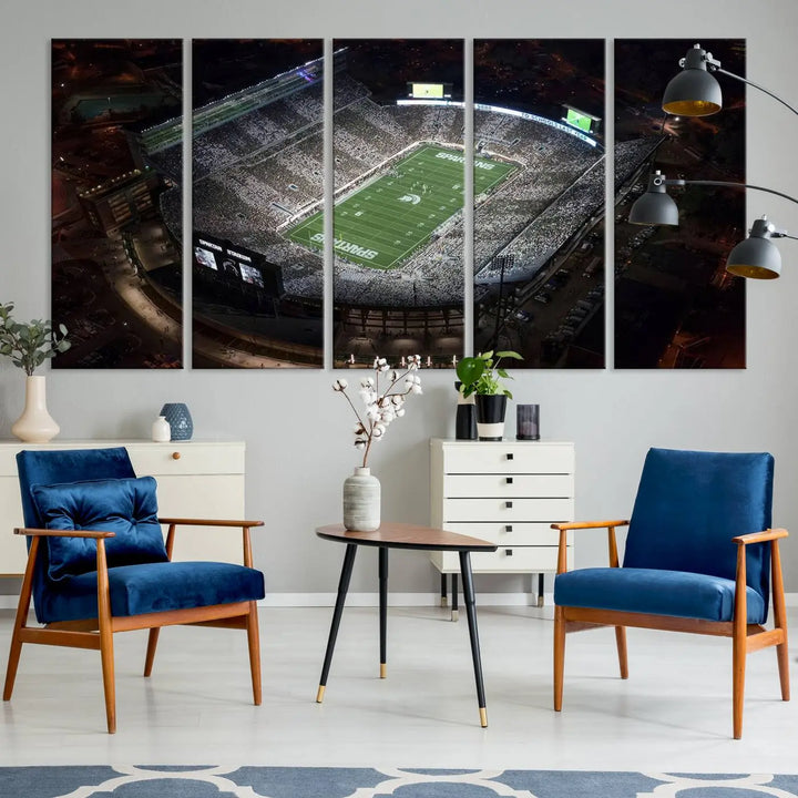 The "Michigan State Spartans Football Team Print - East Lansing Spartan Stadium Wall Art Canvas Print" is elegantly displayed on a wall, showcasing a brightly lit football stadium at night with a gallery-quality finish.