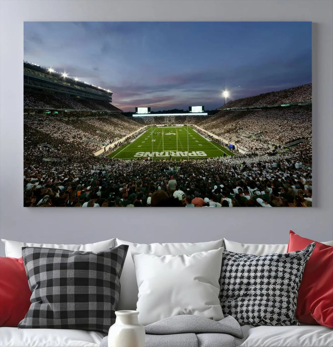 The living room features a Michigan State Spartans Football Team Print, a triptych canvas wall art depicting East Lansing's Spartan Stadium at dusk with a gallery-quality finish.