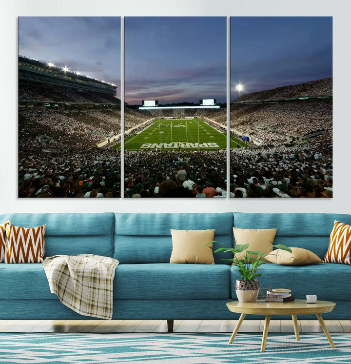 The living room features a Michigan State Spartans Football Team Print, a triptych canvas wall art depicting East Lansing's Spartan Stadium at dusk with a gallery-quality finish.