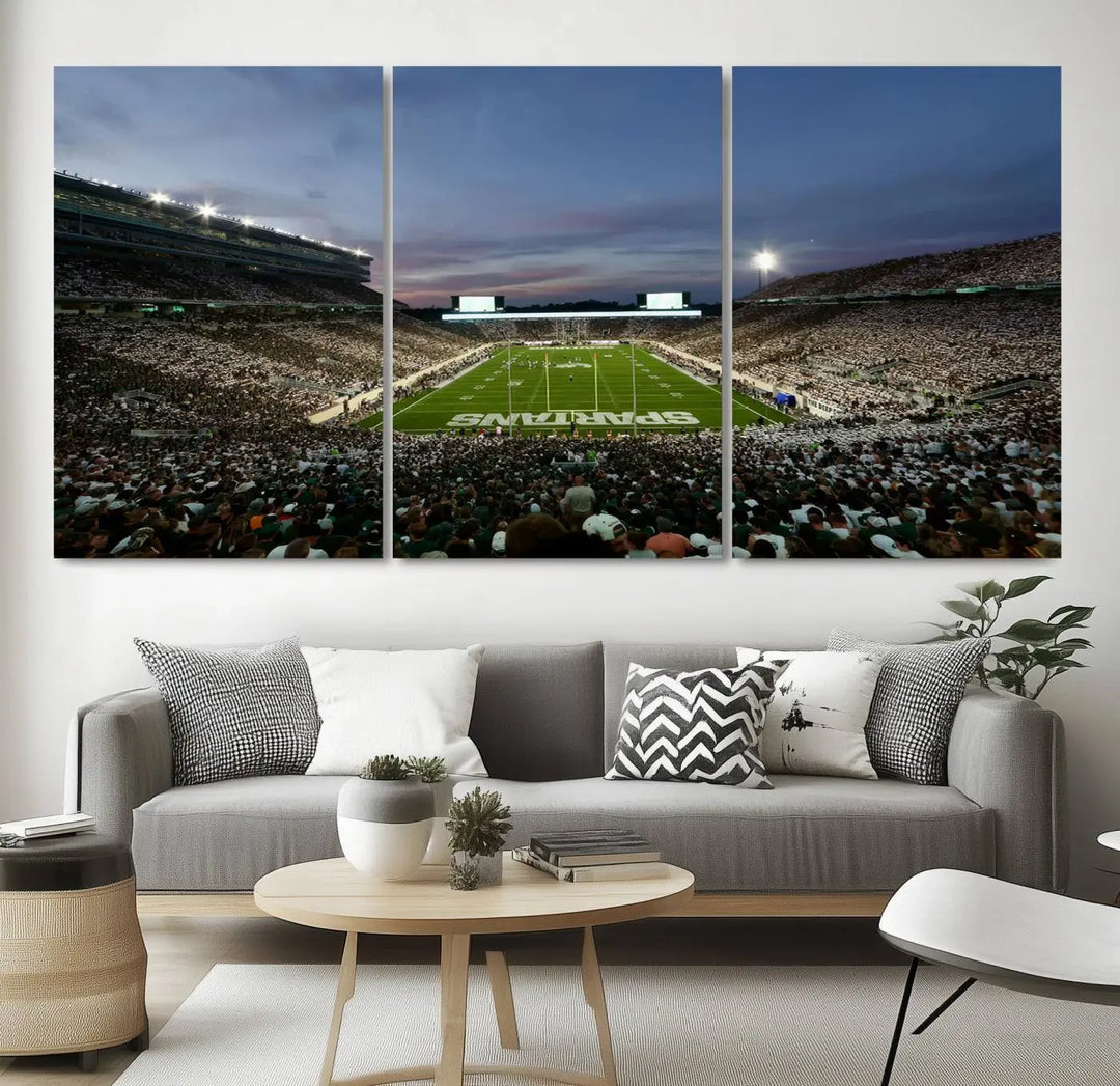 The living room features a Michigan State Spartans Football Team Print, a triptych canvas wall art depicting East Lansing's Spartan Stadium at dusk with a gallery-quality finish.