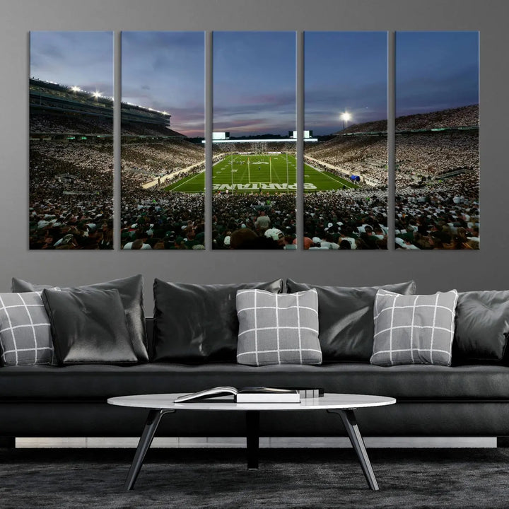 The living room features a Michigan State Spartans Football Team Print, a triptych canvas wall art depicting East Lansing's Spartan Stadium at dusk with a gallery-quality finish.