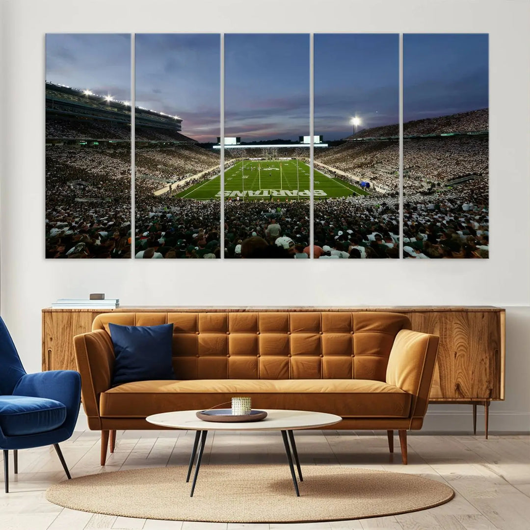 The living room features a Michigan State Spartans Football Team Print, a triptych canvas wall art depicting East Lansing's Spartan Stadium at dusk with a gallery-quality finish.