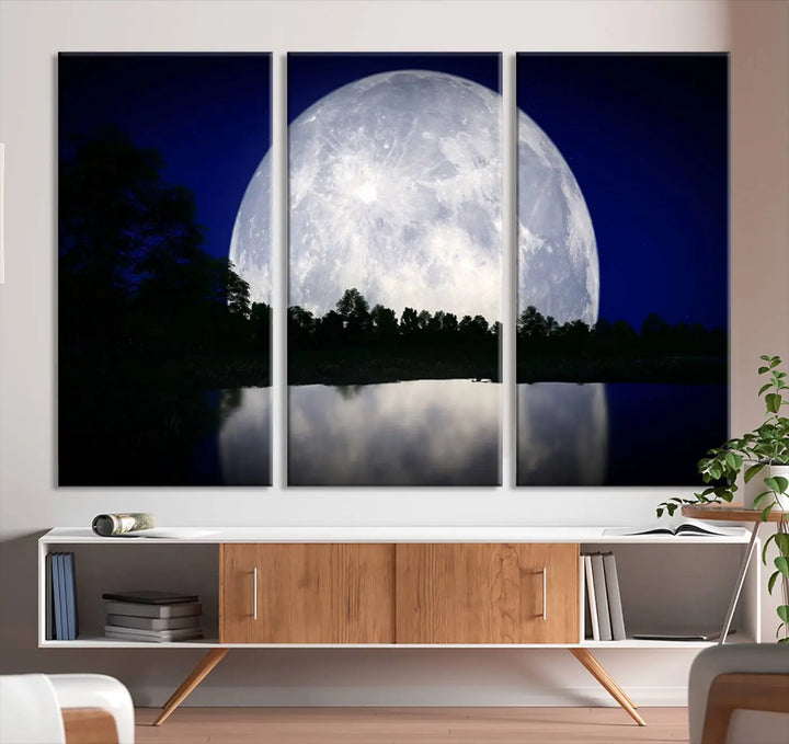 A modern living room showcases a three-panel MoonGlade Wall Art Canvas Print, depicting a moonlit night over a tranquil lake on museum-quality canvases.