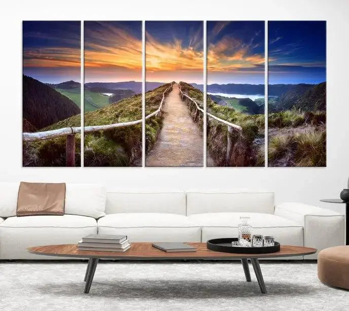 The Mountain and Sunset Wall Art Canvas Print, featuring a three-panel design on museum-quality canvas, captures a stunning sunset over a mountain path with a wooden railing. The hand-assembled frame ensures an exquisite finish and arrives ready to hang, adding natural beauty to any environment.