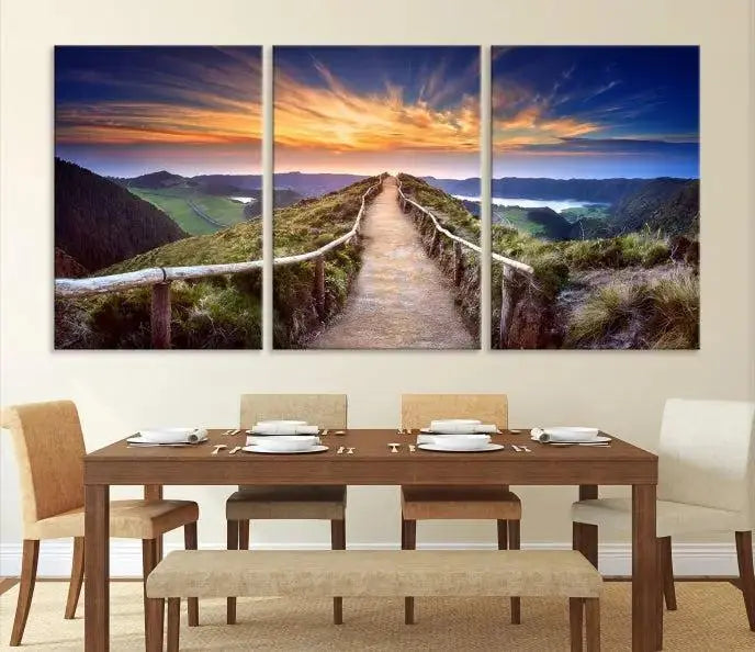 The Mountain and Sunset Wall Art Canvas Print, featuring a three-panel design on museum-quality canvas, captures a stunning sunset over a mountain path with a wooden railing. The hand-assembled frame ensures an exquisite finish and arrives ready to hang, adding natural beauty to any environment.