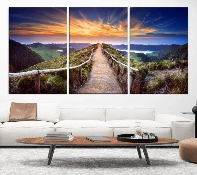 The Mountain and Sunset Wall Art Canvas Print, featuring a three-panel design on museum-quality canvas, captures a stunning sunset over a mountain path with a wooden railing. The hand-assembled frame ensures an exquisite finish and arrives ready to hang, adding natural beauty to any environment.