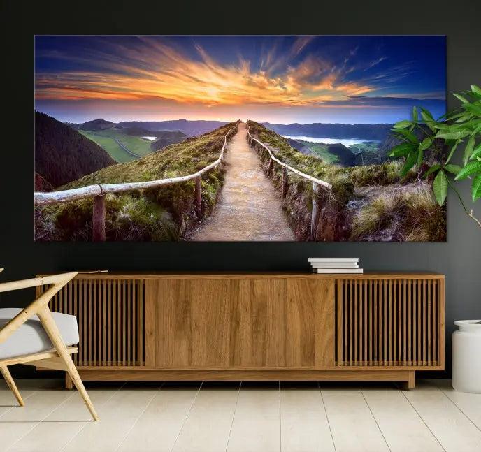 The Mountain and Sunset Wall Art Canvas Print, featuring a three-panel design on museum-quality canvas, captures a stunning sunset over a mountain path with a wooden railing. The hand-assembled frame ensures an exquisite finish and arrives ready to hang, adding natural beauty to any environment.